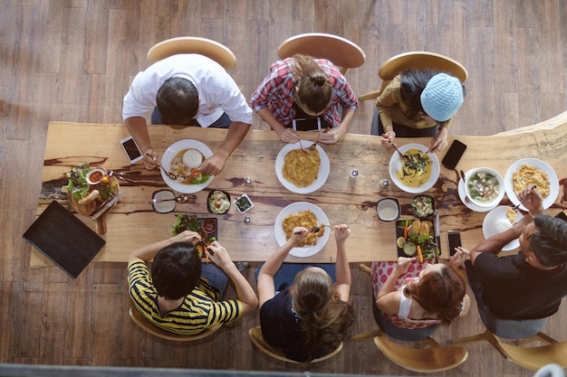 Vista de ángulo alto de amigos comiendo comida en la mesa de comedor