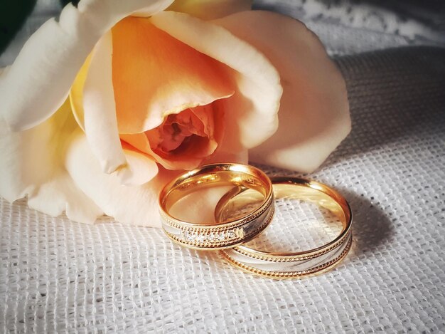 Vista de ángulo alto de los anillos de bodas por la flor en la mesa en casa