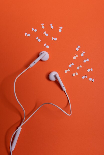 Vista de ángulo alto de los auriculares en la mesa contra un fondo naranja