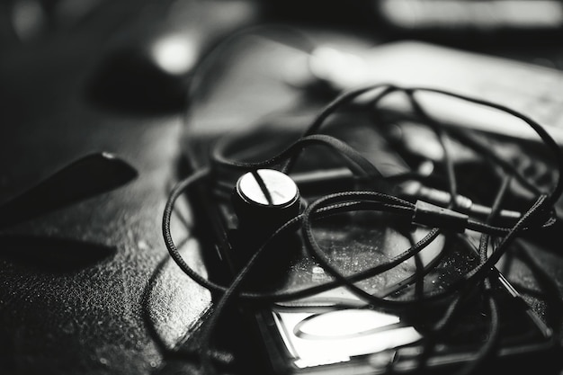 Vista de ángulo alto de auriculares en el oído y teléfono inteligente en la mesa