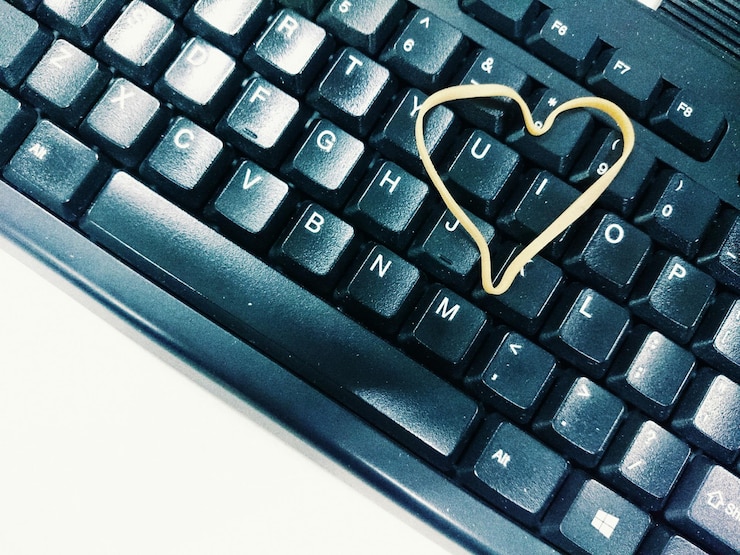 Foto vista de ángulo alto de una banda de goma en forma de corazón en el teclado de la computadora