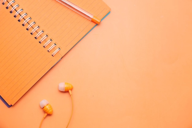 vista de ángulo alto del bloc de notas de color naranja con lápiz sobre fondo naranja