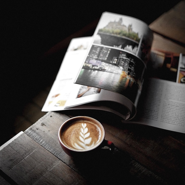 Foto vista de ángulo alto del café por una revista en la mesa contra un fondo negro