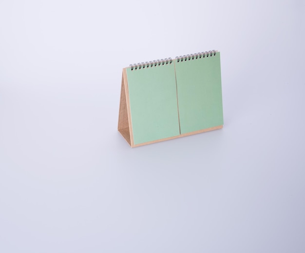 Vista de ángulo alto del calendario de escritorio verde en blanco contra un fondo blanco