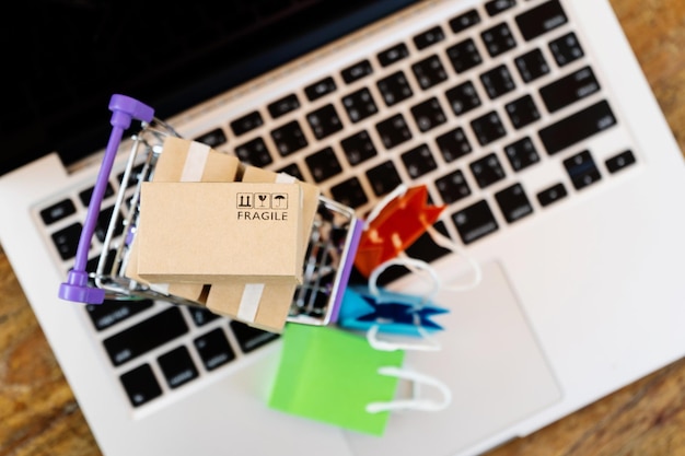 Vista de ángulo alto del carrito de compras sobre la computadora portátil en la mesa