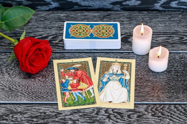 Vista de ángulo alto de las cartas del tarot con velas y rosas en la mesa