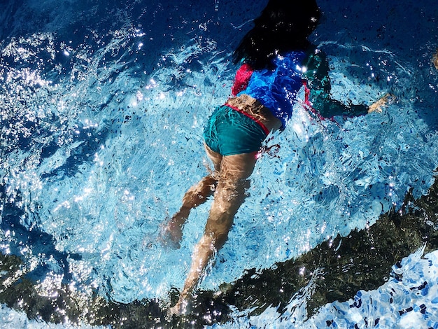 Foto vista de ángulo alto de una chica nadando en la piscina