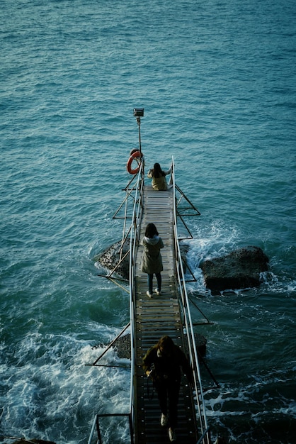 Vista de ángulo alto de la chica de pie en el muelle sobre el mar