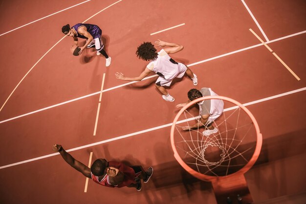 Foto vista de ángulo alto de chicos guapos jugando baloncesto al aire libre por la noche