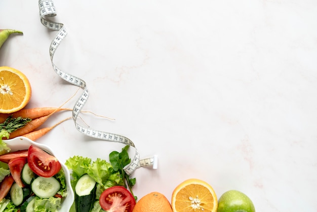 Foto vista de ángulo alto de la cinta métrica cerca de verduras y frutas orgánicas sobre fondo blanco