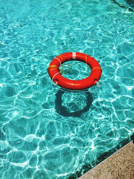 Vista de ángulo alto del cinturón salvavidas rojo flotando en la piscina