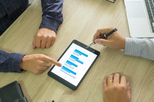 Vista de ángulo alto de colegas analizando gráficos en tableta digital en el escritorio de la oficina