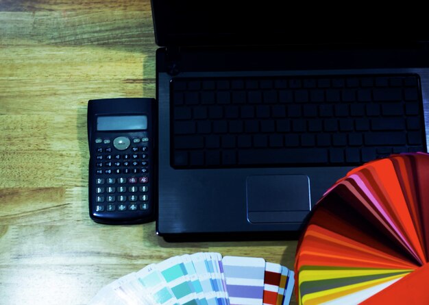 Foto vista de ángulo alto de la computadora portátil con calculadora y muestra de color en la mesa