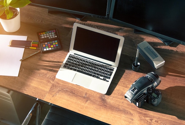 Vista de ángulo alto de la computadora portátil con cámara y lápices de colores en la mesa