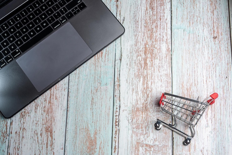 Foto vista de ángulo alto de la computadora portátil y el carrito de compras en la mesa
