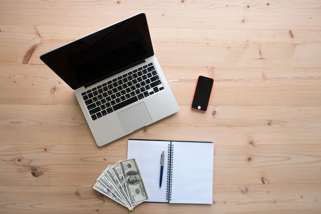 Vista de ángulo alto de la computadora portátil con moneda y diario en la mesa