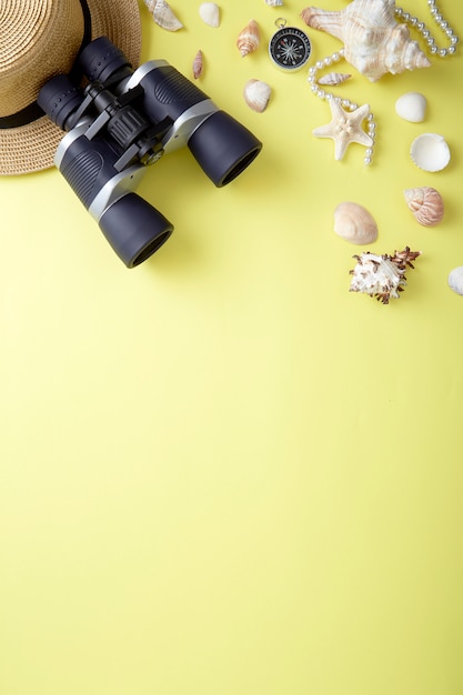 Foto vista de ángulo alto de conchas marinas con binoculares y joyas sobre amarillo