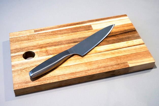 Vista de ángulo alto de un cuchillo de cocina afilado con tabla de corte de madera en la mesa