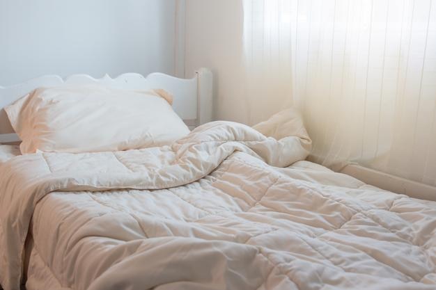 Vista de ángulo alto de un edredón arrugado en una cama vacía en casa