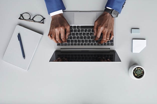 Vista de ángulo alto del empresario escribiendo en la computadora portátil que se comunica en línea en su lugar de trabajo