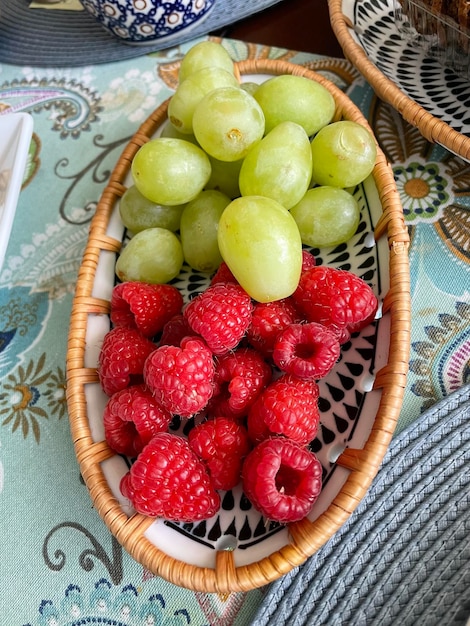 Vista de ángulo alto de frambuesas y uvas en un cuenco en la mesa