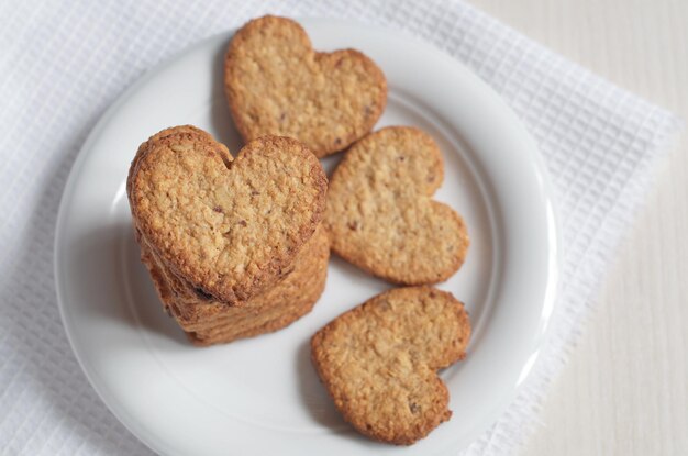 Vista de ángulo alto de galletas de avena en forma de corazón en un plato sobre la mesa. enfoque selectivo