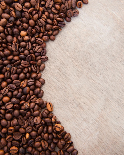 Vista de ángulo alto de granos de café tostados en una mesa de madera
