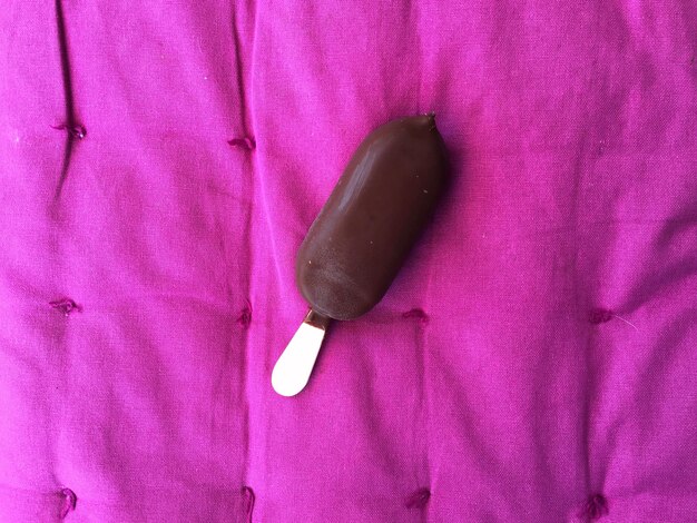 Foto vista de ángulo alto del helado de chocolate en la cama púrpura