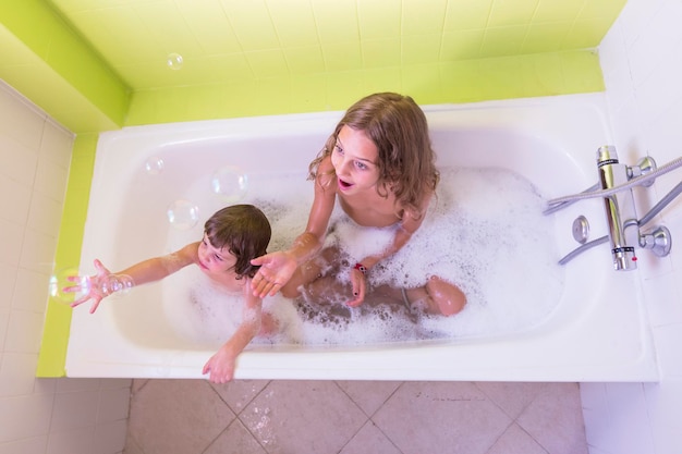 Vista de ángulo alto de hermanos felices jugando en la bañera