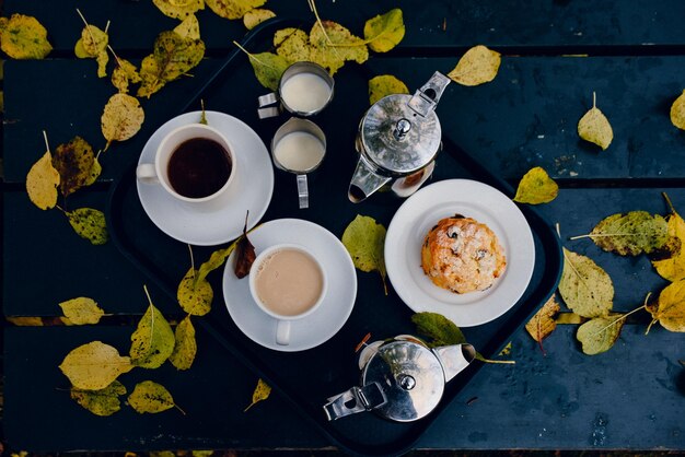 Vista de ángulo alto de las hojas de otoño por el desayuno en la bandeja en la mesa