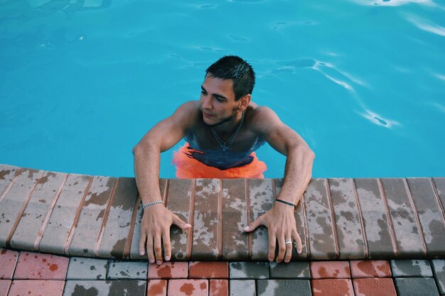 Vista de ángulo alto de un hombre sin camisa nadando en la piscina