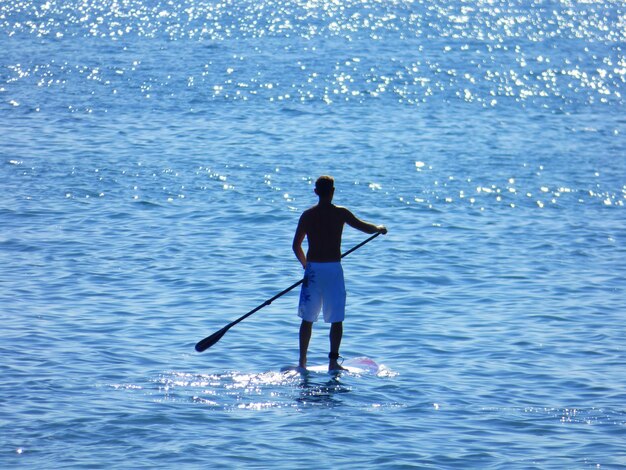 Vista en ángulo alto de un hombre haciendo paddleboard en el mar