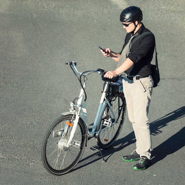 Vista de ángulo alto del hombre de negocios con bicicleta eléctrica usando teléfono celular