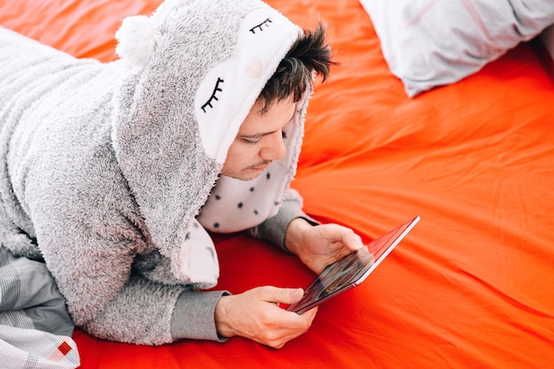 Vista de ángulo alto de un hombre usando el teléfono móvil en la cama