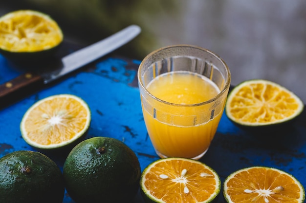 Vista de ángulo alto del jugo de limón fresco por las frutas en la mesa