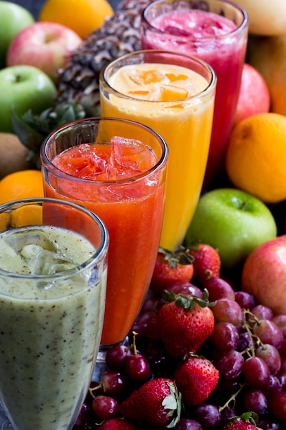 Vista de ángulo alto de los jugos en vasos por las frutas en la mesa