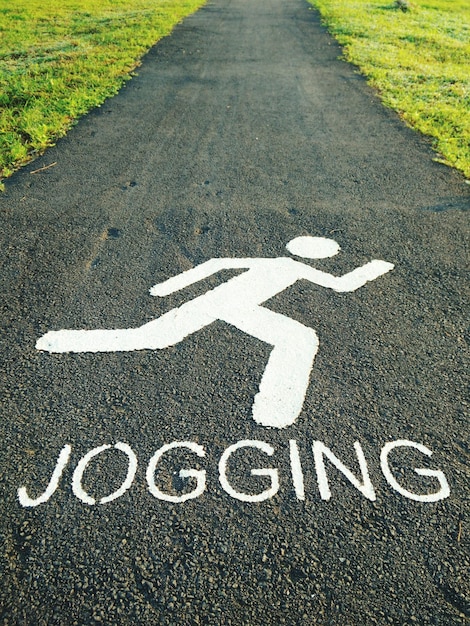 Vista de ángulo alto de un letrero para peatones con texto de jogging en el sendero