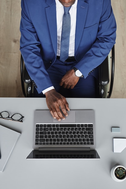 Vista de ángulo alto de líder empresarial en traje trabajando en línea en la computadora portátil en su lugar de trabajo en la oficina