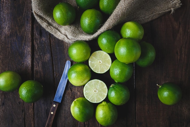 Vista de ángulo alto de limones por saco y cuchillo en mesa de madera