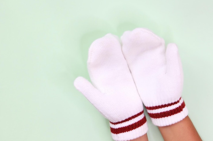 Foto vista de ángulo alto de la mano de la niña con guante sobre un fondo verde