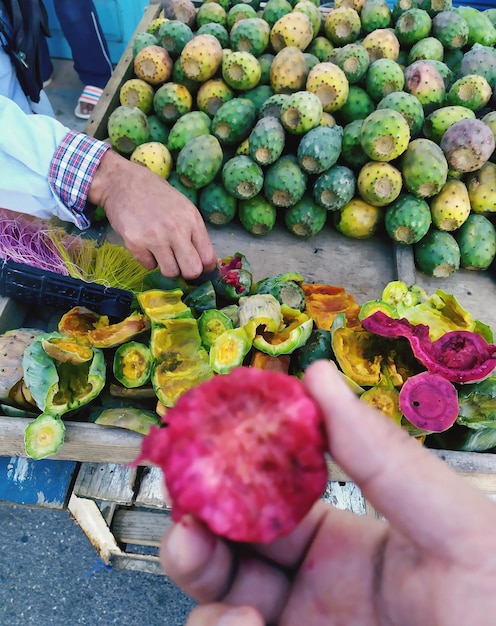 Foto vista de ángulo alto de la mano sosteniendo frutas de higo rosas en el mercado al aire libre en marruecos