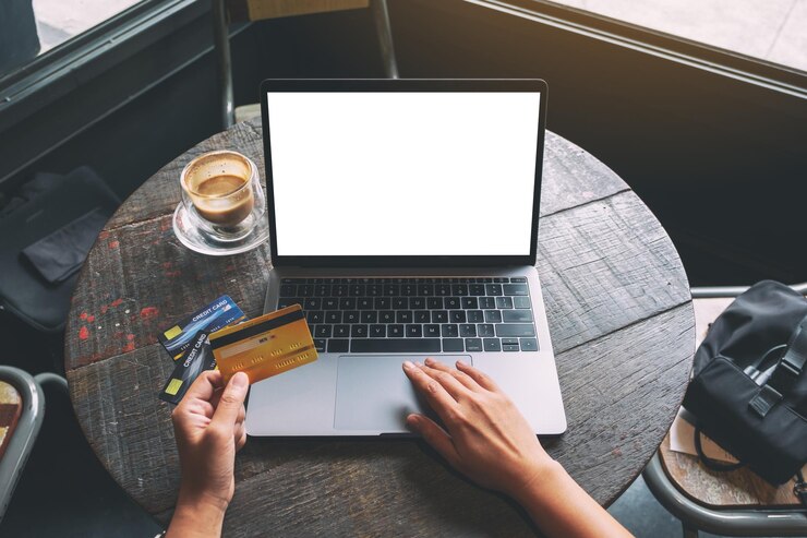 Foto vista de ángulo alto de la mano sosteniendo una tarjeta de crédito mientras usa una computadora portátil para comprar en línea
