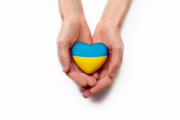 Vista de ángulo alto de las manos del niño sosteniendo la bandera de ucrania corazón pintado aislado sobre fondo blanco