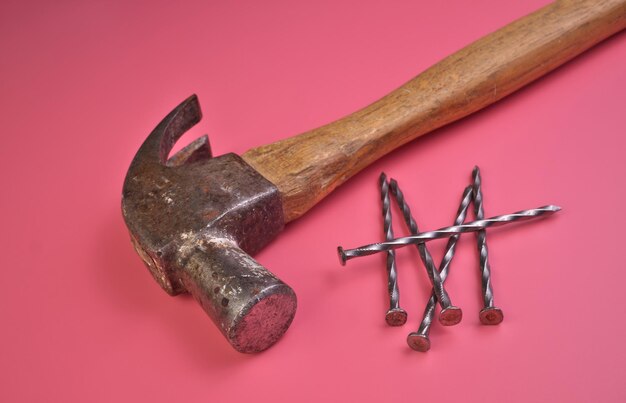 Foto vista de ángulo alto de martillo y clavos aislados en un fondo de estudio rosado