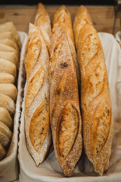 Vista de ángulo alto de muchos panes de baguette hechos a mano frescos en una cesta rústica en una panadería