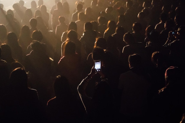 Foto vista de ángulo alto de una mujer fotografiando en medio de la multitud en un concierto de música