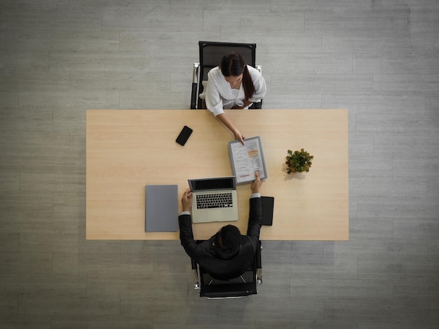 Vista de ángulo alto de una mujer leyendo un libro en la mesa