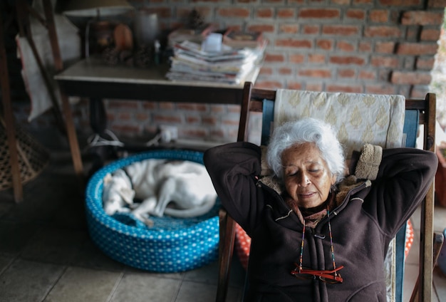 Vista de ángulo alto de una mujer mayor relajándose en una silla en casa