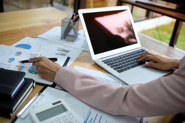 Vista de ángulo alto de una mujer de negocios usando una computadora portátil mientras examina los informes financieros en el escritorio