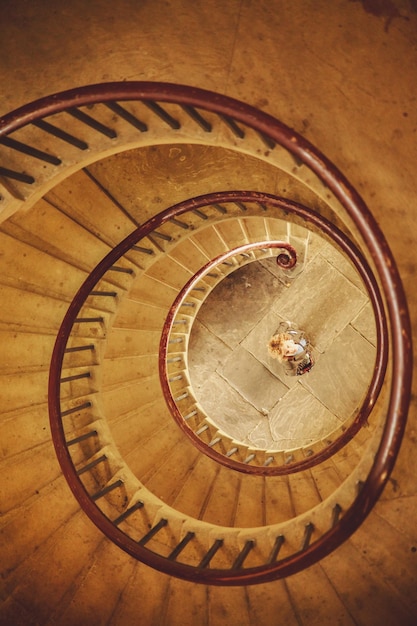 Foto vista de ángulo alto de una mujer de pie debajo de una escalera de espiral